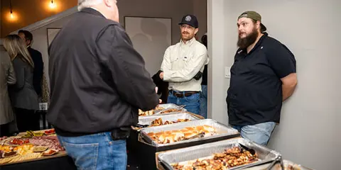 Catering staff serving guests at a buffet event with trays of food.