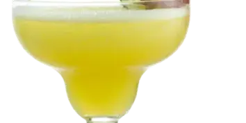 A glass of yellow margarita garnished with a strawberry, kiwi, and orange slice.