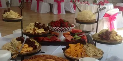 A catering buffet table with assorted appetizers, fruit, and crackers set up in a decorated event hall.