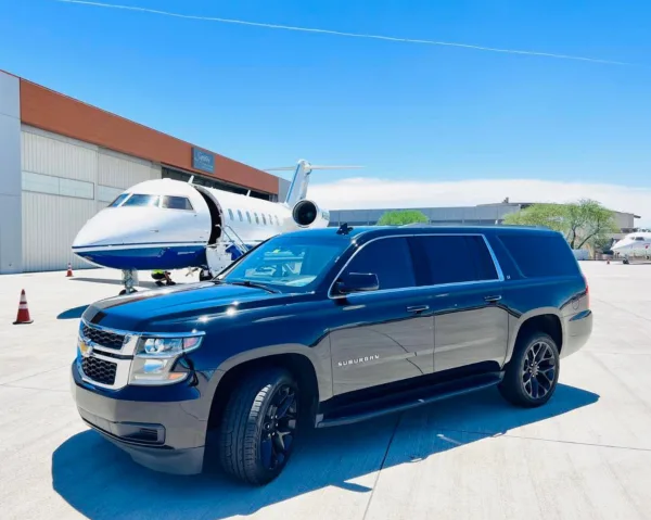 A black luxury SUV parked in front of a private jet at an airport.