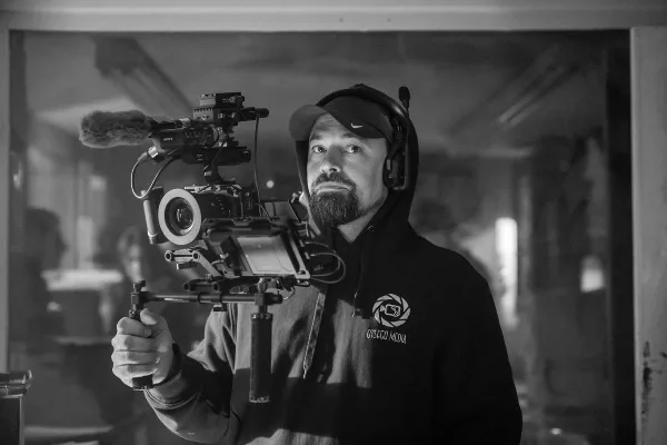 A man wearing an Otsego Media hoodie operates a professional cinema camera rig with a microphone.