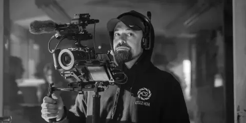 A man wearing an Otsego Media hoodie operates a professional cinema camera rig with a microphone.