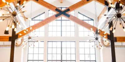 Wedding ceremony in a modern rustic venue with high ceilings, exposed wooden beams, and large windows.