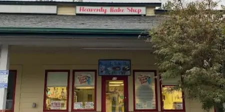 Exterior view of the Heavenly Bake Shop storefront with red doors and signage.