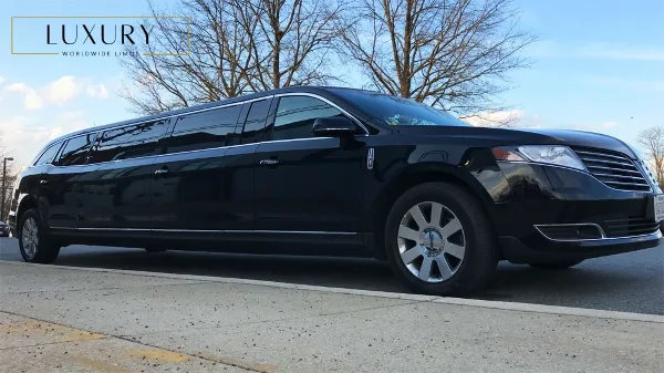 A black stretch limousine parked on a street with a logo overlay in the top left corner.