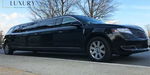 A black stretch limousine parked on a street with a logo overlay in the top left corner.