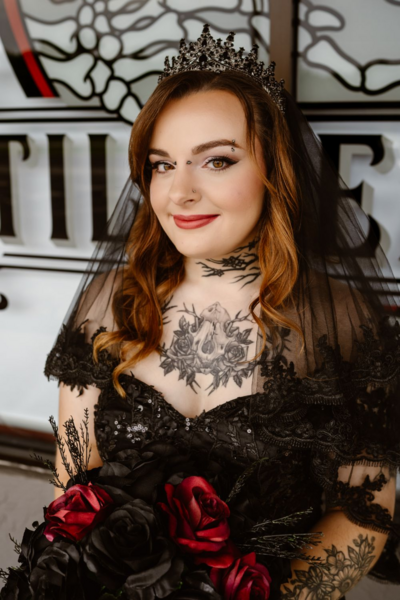 Portrait of a bride with styled hair and makeup, wearing a black lace dress and tiara.