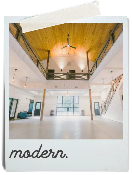 Interior view of a modern rustic event venue with high wooden ceilings and white walls.