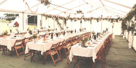 A banquet hall set up for an event with long tables, white tablecloths, and floral centerpieces.