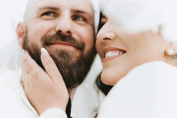Close-up portrait of a smiling groom and bride sharing an intimate moment.
