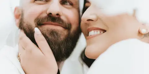 Close-up portrait of a smiling groom and bride sharing an intimate moment.