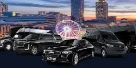 A lineup of black luxury vehicles including a sedan, SUV, and van parked in front of a city skyline at dusk.