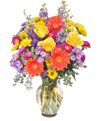 A colorful floral bouquet featuring yellow roses, orange gerbera daisies, and purple asters arranged in a clear glass vase.