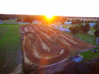 Aerial view of the Posey County Fairgrounds showing the dirt track and surrounding fields at sunset.