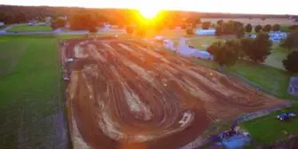 Aerial view of the Posey County Fairgrounds showing the dirt track and surrounding fields at sunset.