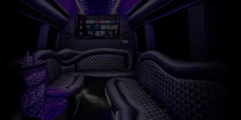 Interior view of a luxury party bus with quilted leather seating and a large entertainment screen.