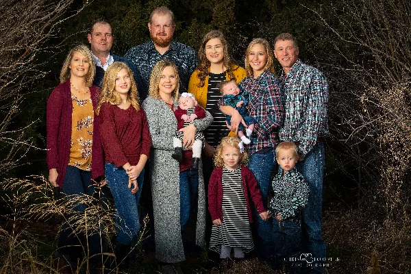 A professional outdoor family portrait of a multi-generational group including adults, children, and infants, with the Chris Loeffler Photography logo in the corner.