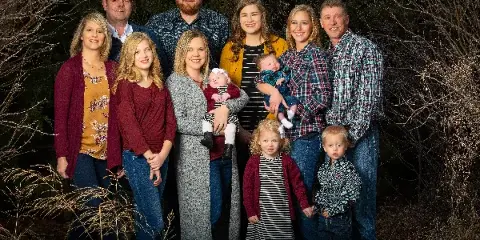 A professional outdoor family portrait of a multi-generational group including adults, children, and infants, with the Chris Loeffler Photography logo in the corner.