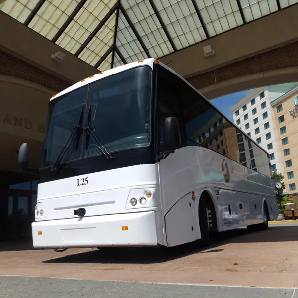 A white St. Louis Transportation motor coach parked at a hotel entrance.