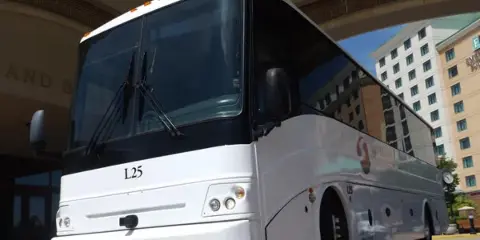 A white St. Louis Transportation motor coach parked at a hotel entrance.