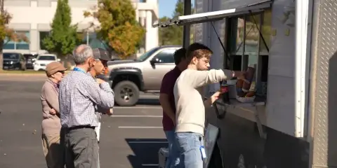A food truck serving customers in a parking lot.