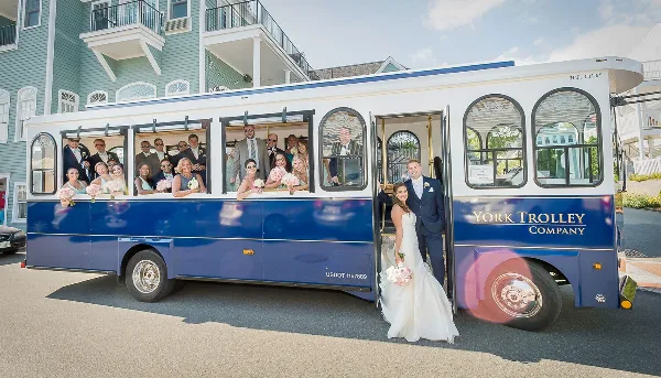 A blue and white open-air trolley with 'YORK TROLLEY COMPANY' written on the side, carrying a wedding party including a bride and groom.