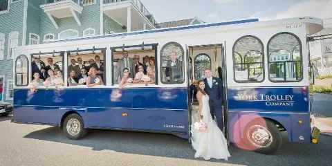 A blue and white open-air trolley with 'YORK TROLLEY COMPANY' written on the side, carrying a wedding party including a bride and groom.