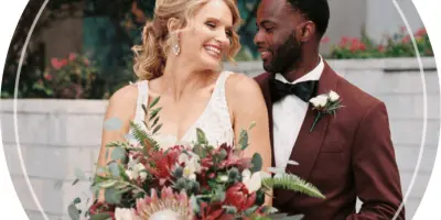 A bride and groom standing together, with the bride holding a large, colorful bouquet of flowers.