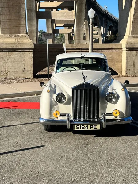 A classic silver Rolls-Royce parked outdoors in bright sunlight.
