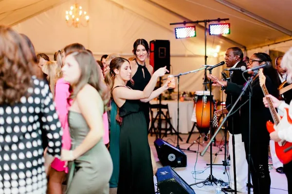 A live band performing on stage at a wedding reception with guests dancing.