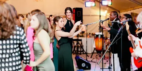 A live band performing on stage at a wedding reception with guests dancing.