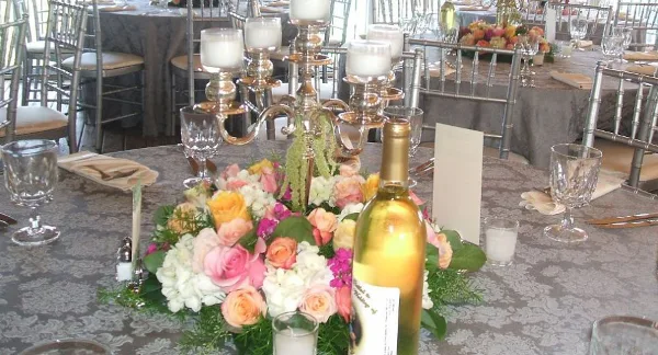 Elegantly set wedding reception table with floral centerpiece, candles, and glassware.