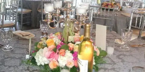 Elegantly set wedding reception table with floral centerpiece, candles, and glassware.