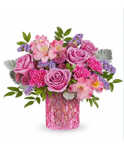 A vibrant floral arrangement featuring pink roses, alstroemeria, and purple filler flowers in a textured pink vase.