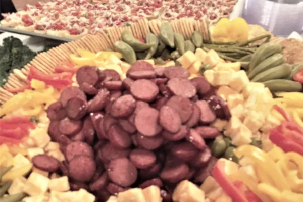 A catering platter featuring sliced sausage, cheese, and vegetables.
