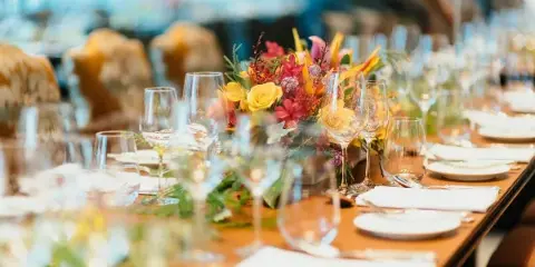 A professionally styled event table featuring a vibrant floral centerpiece, glassware, and white napkins.