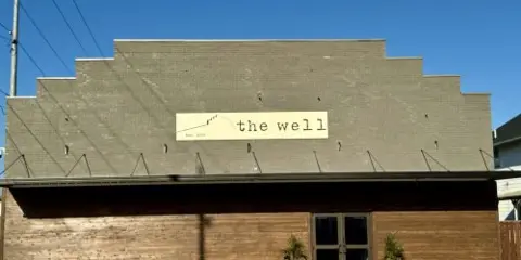 Exterior view of The Well Event Center building featuring a distinctive stepped roofline and brick facade.