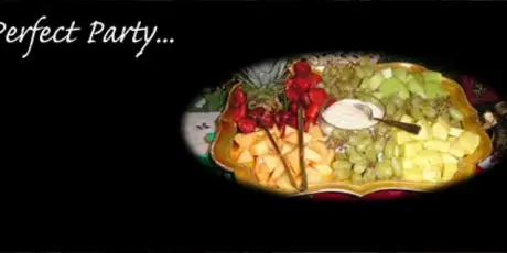 A catering platter featuring an assortment of fresh fruit including strawberries, grapes, and melon with a central dip.