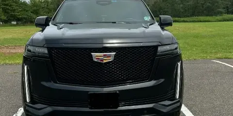 Front view of a black Cadillac Escalade luxury SUV parked in a lot.