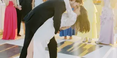 A bride and groom dancing on a checkered dance floor at a rooftop wedding reception with guests in the background.
