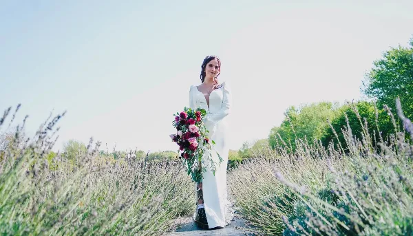 A bride in a white dress holding a bouquet of flowers in a lavender field.