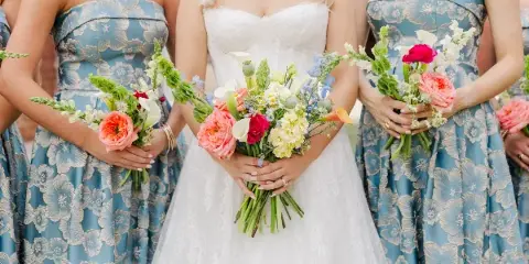 Bride and bridesmaids in blue floral dresses holding colorful wedding bouquets