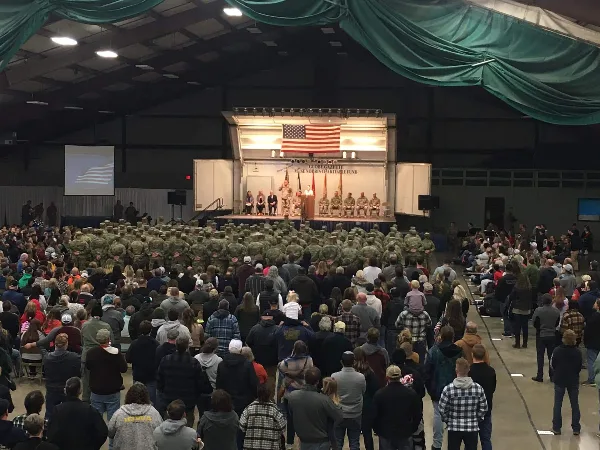 Large indoor event hall with a stage, American flag, and seated audience at a formal gathering.