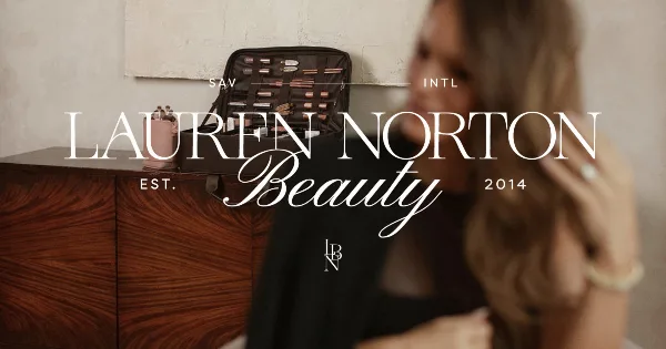 A makeup artist's open professional kit on a wooden dresser with a woman in the background, branded Lauren Norton Beauty.