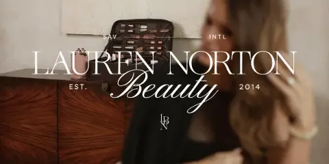 A makeup artist's open professional kit on a wooden dresser with a woman in the background, branded Lauren Norton Beauty.