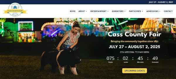 A girl leading a pig at the Cass County Fair with carnival rides in the background.