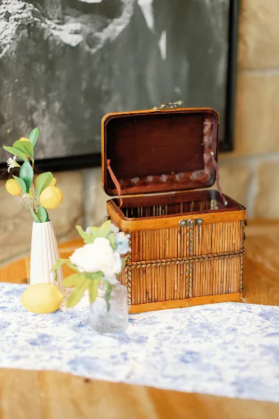 A decorative wooden basket and floral accents arranged on a table with a blue and white patterned runner.