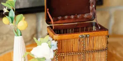 A decorative wooden basket and floral accents arranged on a table with a blue and white patterned runner.