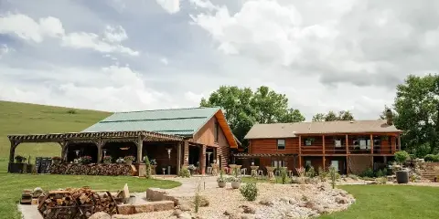 Exterior view of the Big Vista Ranch main lodge and patio area featuring log construction, a green metal roof, and outdoor seating.