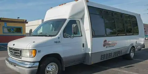 White shuttle bus with Bakersfield Party Buses branding parked in a lot